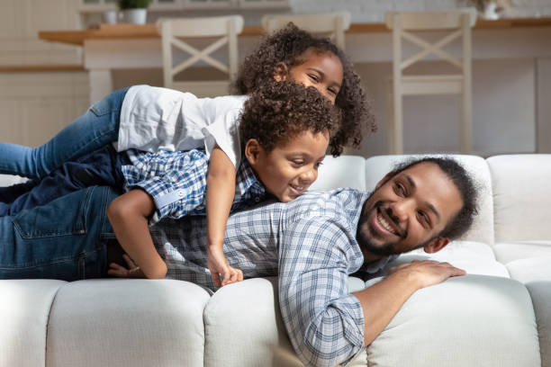 istock African children piled on their father lying on sofa indoor 2078161591