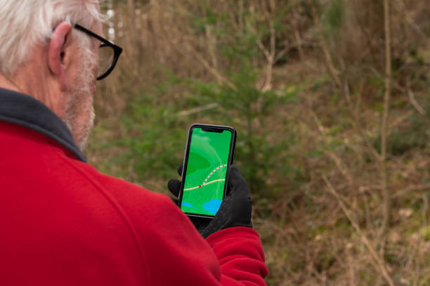 Senior man in a woodland location in Scotland looking at a map app on his mobile phone