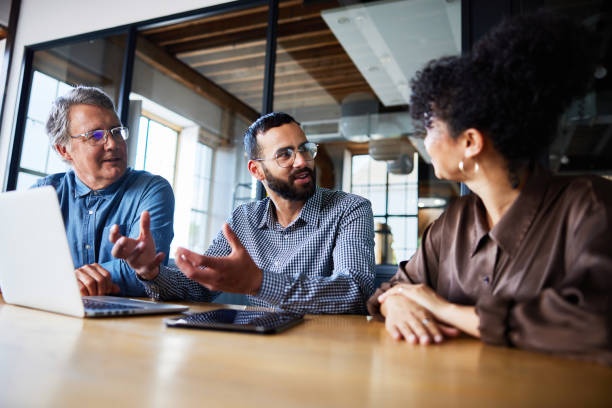 istock Smiling businesspeople talking and working on a laptop together at an office table 2078172603