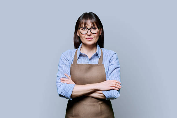 istock Confident serious middle-aged woman in apron on gray background 2078174182