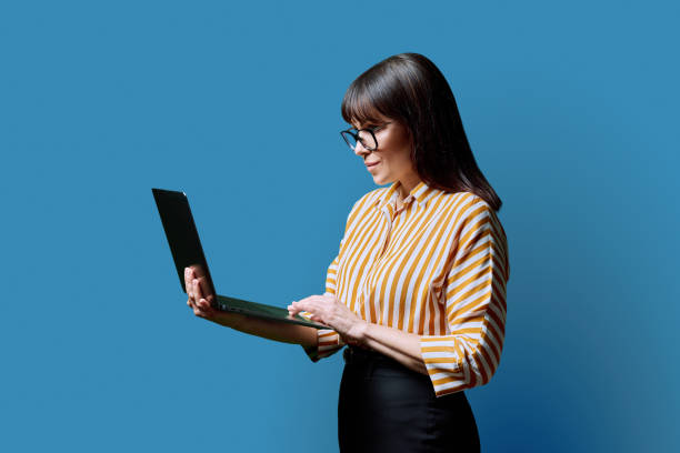 istock Middle aged business woman using laptop on blue background 2078175245