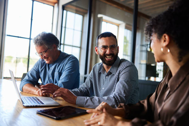 istock Laughing businesspeople working on a laptop together at an office table 2078176847