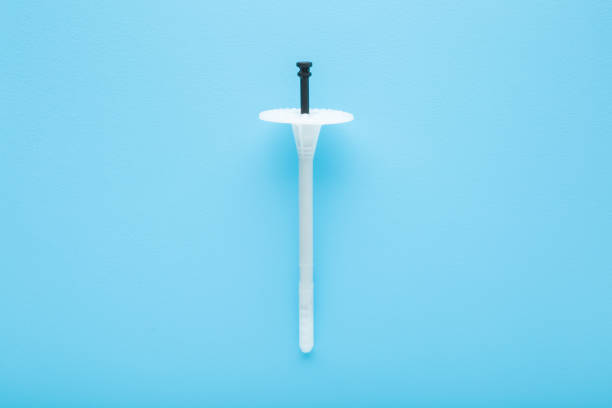 New white plastic insulation anchor dowel for styrofoam panels on light blue table background. Pastel color. Closeup. Top down view.