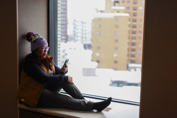 istock Woman sitting by window using mobile phone 2078178460