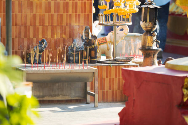 Altar with many smoking aroma incense sticks in front of small elephant statues. Burning incense sticks outdoors at temple. Offering for the deities at Thailand. Blurred foreground