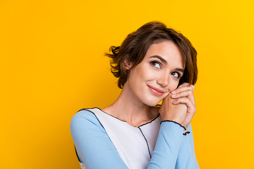 Photo of dreamy adorable woman wear top arms cheek looking empty space isolated yellow color background.