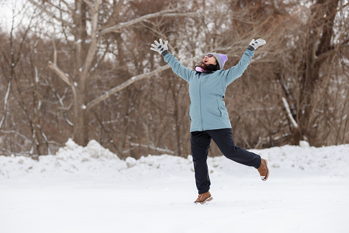Happy young woman enjoying winter playing in snow