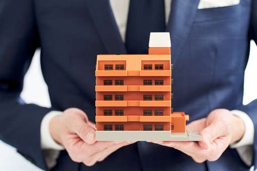 Businessman's hand holding a model of an apartment