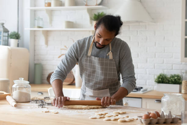 istock African man rolls out the dough for preparing biscuits 2078186022