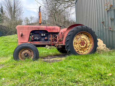 Old farm tractor in a field in Saskatchewan, on a slightly cloudy day. The tractor is still hooked up to farm equipment, as if one day, the farmer just parked it there and was going to come back to finish his fields.