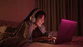 Teenage girl using laptop in bed at night.