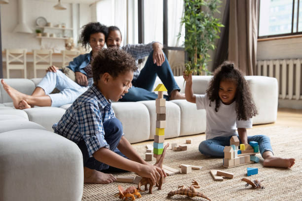 istock African siblings play on warm floor, parents relaxing on sofa 2078190178