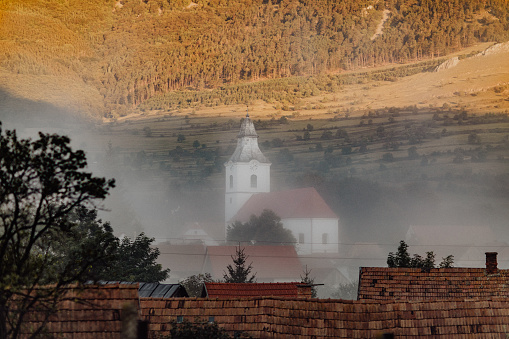 Morning Fog over the Church Tower in Rimetea Village.  Sunny meadow.
