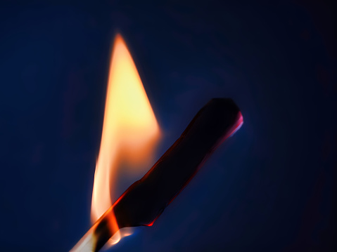 Close up of a lit matchstick in front of a black background