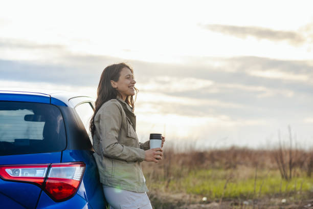 Photo of a beautiful woman standing next to the car and enjoying the view