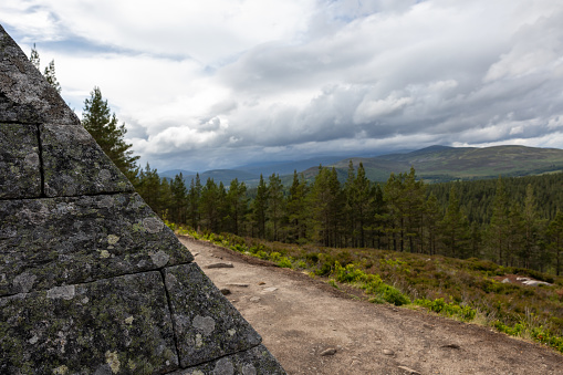 Crathie, Scotland, UK – June 19th, 2023: View over the wooded hills of the Cairngorms with menacing clouds hanging above, seen along the Prince Albert's Pyramid on the Balmoral Estate.