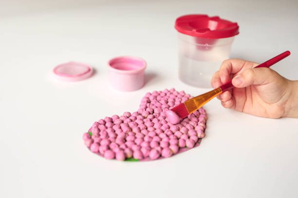 Mother with her daughter making beaded jewelry at home, closeup