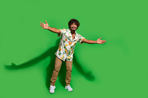 Full length photo of cool friendly latin guy dressed print shirt open arms ready hug you empty space isolated green color background.