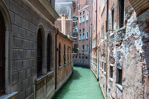 Venice, Veneto - Italy - 06-09-2021: A secluded waterway meanders between weathered walls in Veniceâs quiet quarter