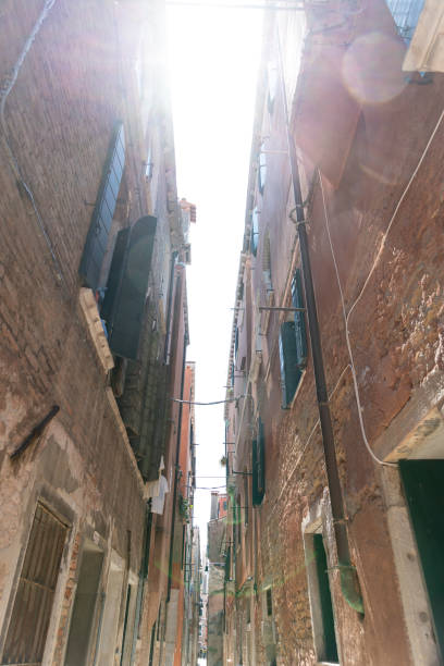 Venice, Veneto - Italy - 06-09-2021: View up a slender Venetian alley to the bright sky above