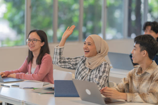Asian female student rise hand Asian female student rise hand question lecture query malaysia students stock pictures, royalty-free photos & images