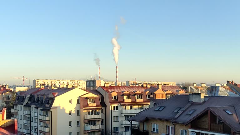 Chimneys of thermal power plant smoke against the backdrop of the city and roofs. Bialystok, Poland