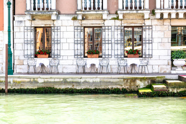 Venice, Veneto - Italy - 06-10-2021: Elegant Venice cafÃ© by the canal, featuring ornate iron chairs and window guards and waterside seating