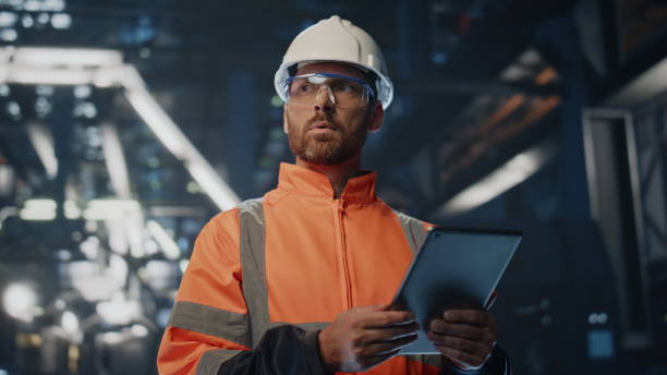 istock Serious factory supervisor looking at manufacturing making notes tablet close up 2078259499
