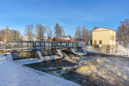 Water flushing from an open gate at a hydro electric power plant in Sweden, in wintertime with snow and sunlight