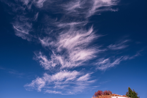 Expressive shapes of spectacular clouds over a mountain hill covered with forest in the autumn season