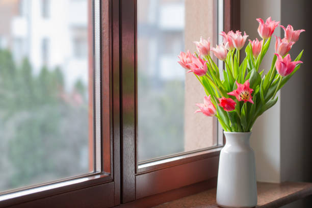istock pink tulips in vase on windowsill 2078279904