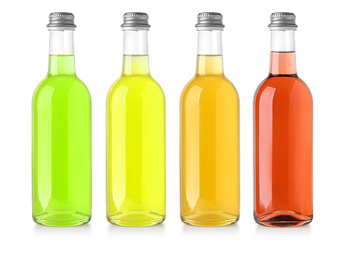 Back lit photo of a large assortment of multi colored glass bottles shot on reflective white backdrop. The bottles are arranged so that the taller are in the center at the background while the smaller are at the sides and in the foreground. The bottles are of different shapes, color and sizes. Visible reflection of the bottles in the foreground. High key DSLR studio photo taken with a Canon 5D Mk II.