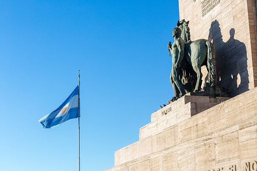 Rosario, Santa Fe, Argentina - June 28, 2023: \nNational Flag Memorial, lateral view of the main tower. The Argentine Flag in foreground. Monumento a la Bandera.