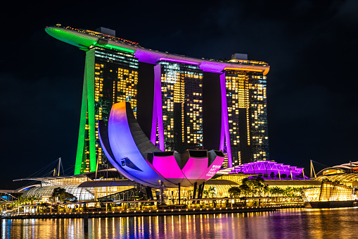 Singapore, 8 March 2024: Marina Bay Sands in Singapore its vibrant illumination mirrored in surrounding waters. ArtScience Museum and Helix Bridge enhance to vibrant, modern skyline