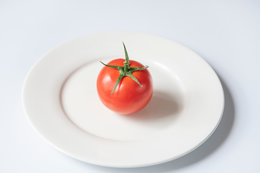 There is a tomato on the white plate