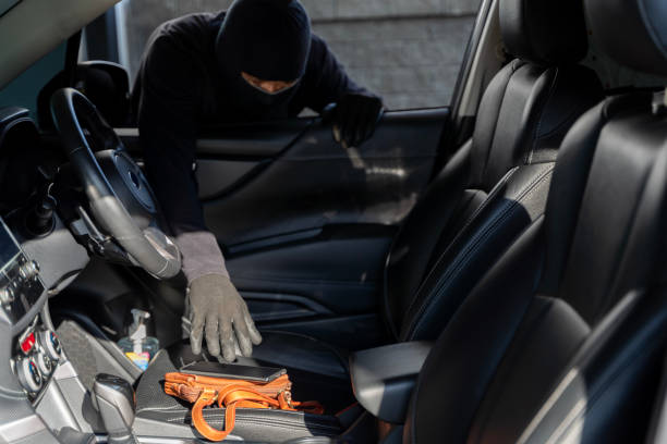 les objets personnels de valeur laissés sur le siège avant sont faciles à attraper pour les voleurs. une main qui sort un portefeuille du siège passager d’une voiture. - car leather hide seat photos et images de collection