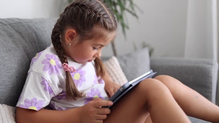 Adorable little girl use tablet at home. Five year old girl play games on tablet