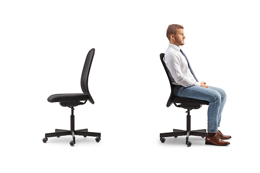 Businessman sitting in an office chair back to back with an empty chair isolated on white background