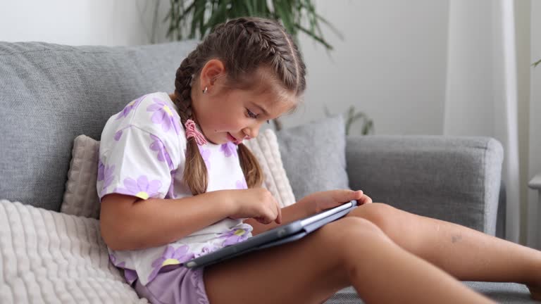 Adorable little girl use tablet at home. Five year old girl play games on tablet