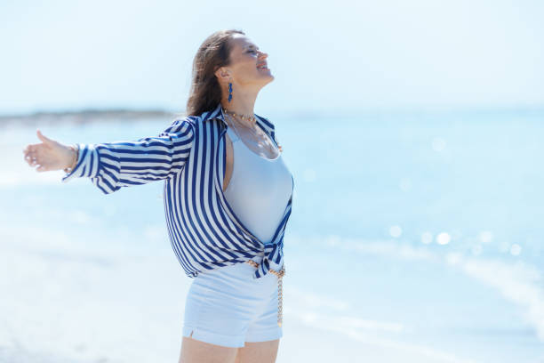 istock happy elegant female on ocean shore rejoicing 2078334834
