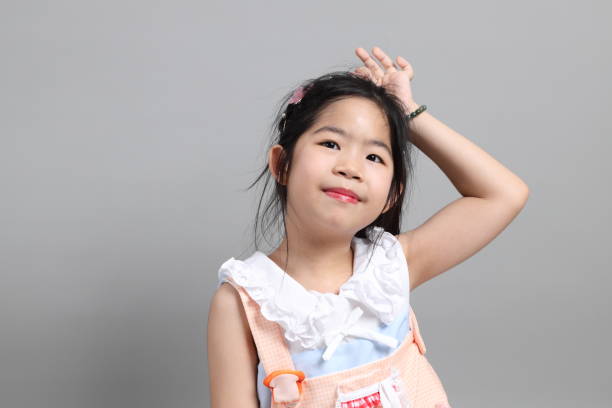 The little cut Asian girl with fancy dressed standing on the grey background.