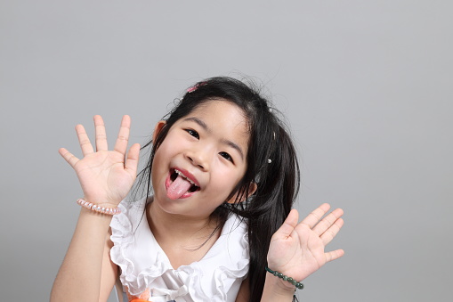 The little cut Asian girl with fancy dressed standing on the grey background.