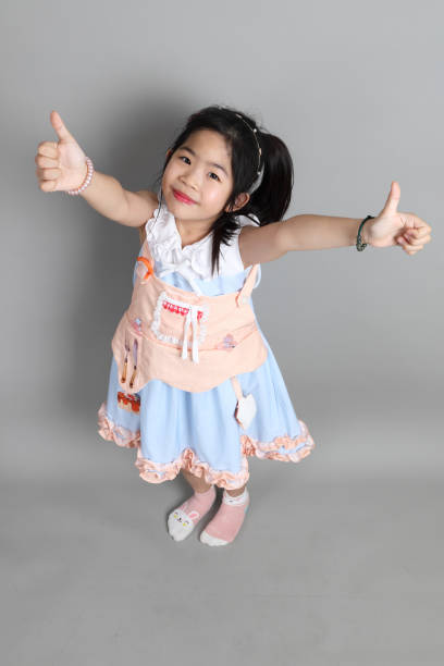 The little cut Asian girl with fancy dressed standing on the grey background.