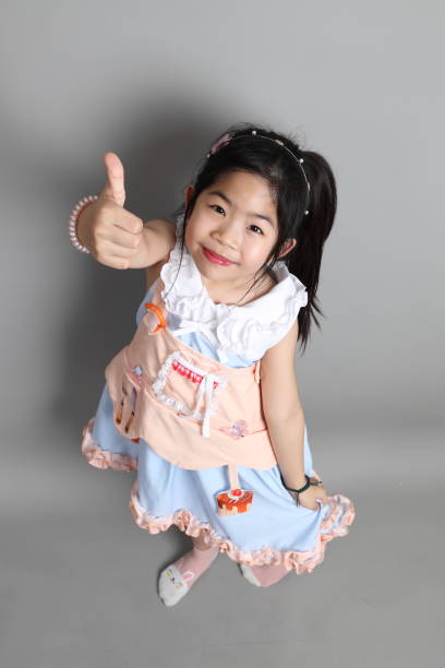 The little cut Asian girl with fancy dressed standing on the grey background.