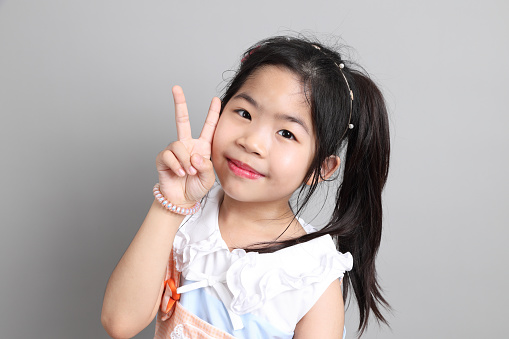 Portrait of a cute smiling girl wearing white dress, close-up. Happy child girl on white background with copy space