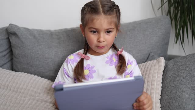 Adorable little girl use tablet at home. Five year old girl play games on tablet