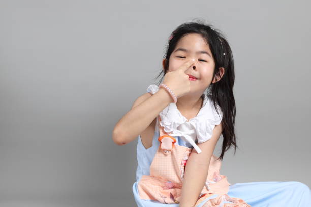 The little cut Asian girl with fancy dressed standing on the grey background.