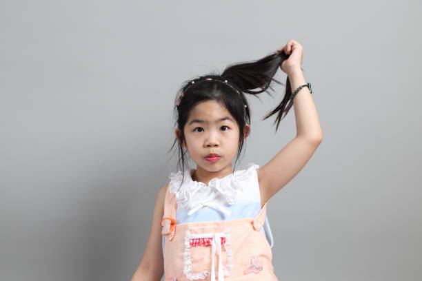The little cut Asian girl with fancy dressed standing on the grey background.