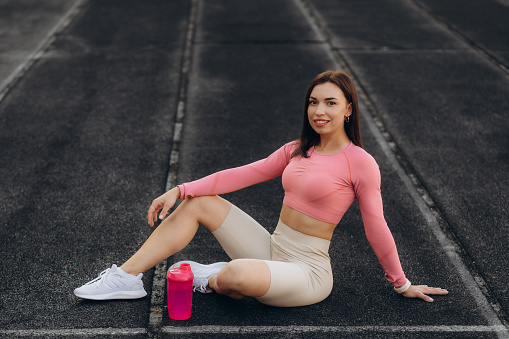 Woman in sports clothing sitting on running track