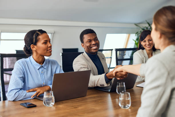 istock A smiling black businessman doing a handshake with a female client, sitting with two other females. 2078355556